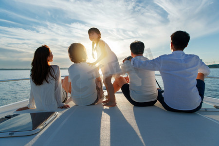海边夕阳天空摄影照片_夕阳下坐在游艇上的快乐一家人