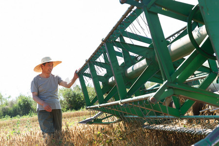 科技耕地摄影照片_农田里实现机械化收割的农民