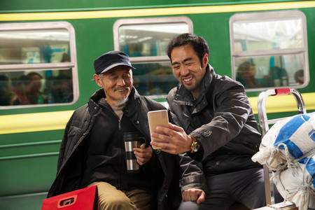 春运火车摄影照片_在火车站台上看手机的旅客