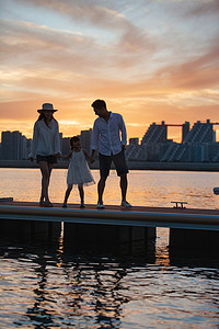 生活建筑剪影摄影照片_夕阳下一家三口在海边玩耍