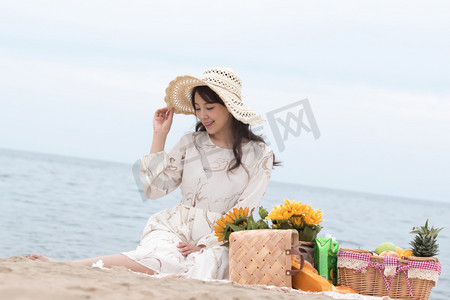 海滩游玩摄影照片_快乐的青年女人坐在沙滩上