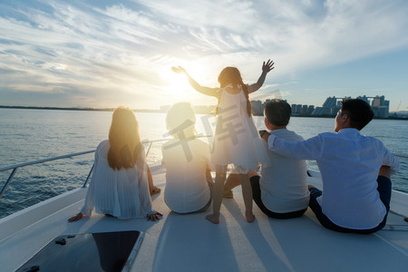 夕阳下的人摄影照片_夕阳下坐在游艇上的快乐一家人