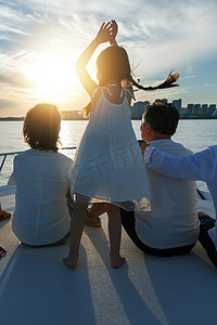 可爱的游艇摄影照片_夕阳下在游艇上的快乐一家人