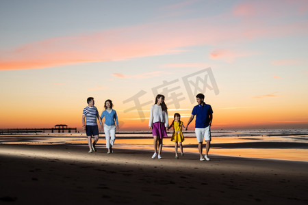 海滩游玩摄影照片_夕阳下在海边散步的幸福家庭