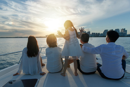 海边夕阳天空摄影照片_夕阳下坐在游艇上的快乐一家人