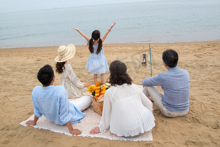 海滩游玩摄影照片_在海边度假的一家人野餐