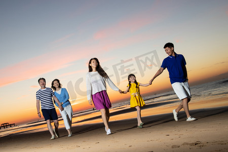 海滩游玩摄影照片_夕阳下在海边散步的幸福家庭