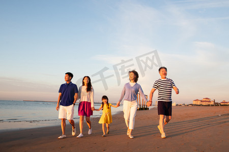 夕阳下的人摄影照片_夕阳下在海边散步的幸福家庭