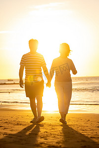 海滩晚霞摄影照片_老年夫妇在海边散步