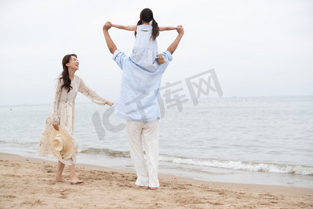 海滩游玩摄影照片_幸福的一家三口在海边玩耍