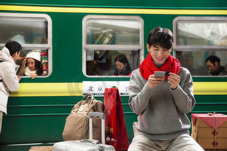 春运火车摄影照片_在火车站台上用手机的青年男人