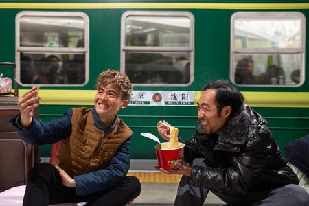 红年货摄影照片_两名男子在火车月台上看手机