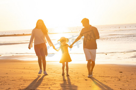 夕阳下一家三口在海边玩耍