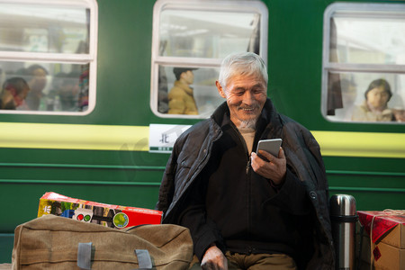春节老人摄影照片_在火车站台上用手机的老人