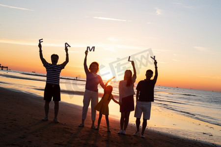 海边晚霞摄影照片_在海边度假的快乐家庭
