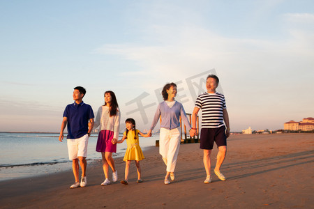 海边夕阳天空摄影照片_夕阳下在海边散步的幸福家庭