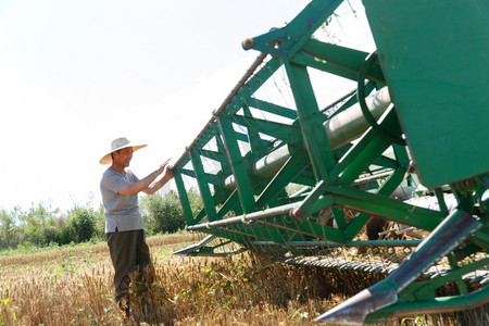 耕地农民摄影照片_农田里实现机械化收割的农民