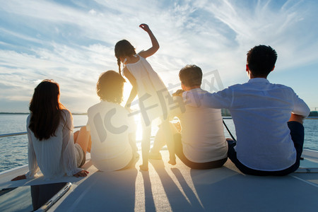 交通安全日摄影照片_夕阳下坐在游艇上的快乐一家人