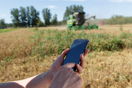 耕地图片摄影照片_农民站在麦田里使用手机