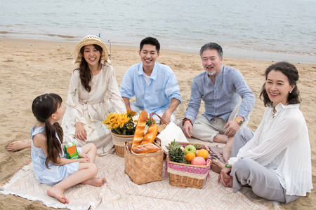 海滩游玩摄影照片_在海边度假的一家人野餐
