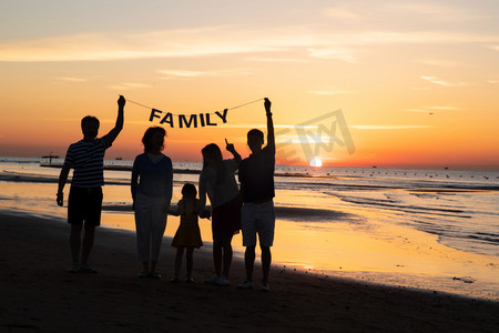 海边晚霞摄影照片_在海边度假的快乐家庭