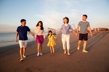 夕阳下在海边散步的幸福家庭