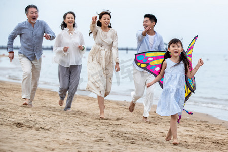 风筝摄影照片_快乐的一家人在海滩上放风筝