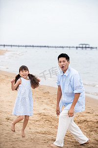 夏日海边沙滩玩耍摄影照片_快乐父女在海边玩耍