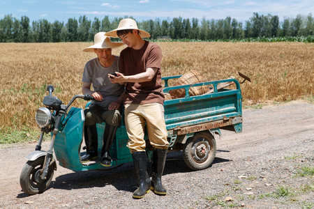 农民坐在三轮车上使用手机