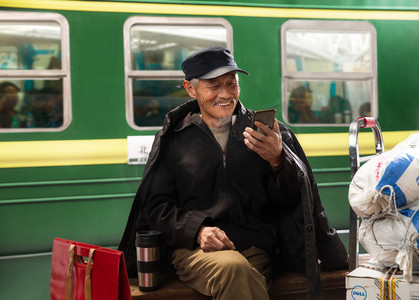 在火车站台上用手机的老人