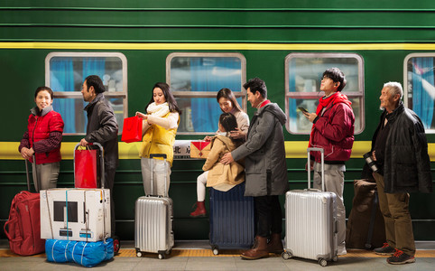 城市摄影照片_站在火车月台上排队上车的旅客
