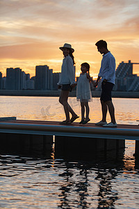 城市出游摄影照片_夕阳下一家三口在海边玩耍