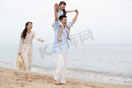 一家三口人物摄影照片_幸福的一家三口在海边玩耍