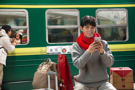 在火车站台上用手机的青年男人