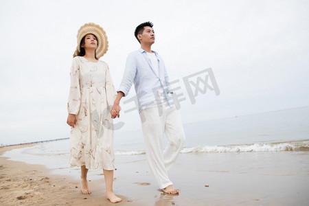 海滩游玩摄影照片_浪漫的青年夫妇在海边散步