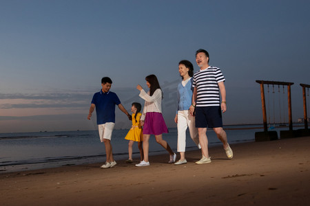 海边夕阳天空摄影照片_夕阳下在海边散步的幸福家庭
