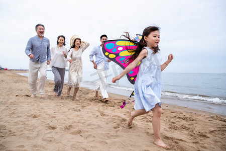 海滩游玩摄影照片_快乐的一家人在海滩上放风筝
