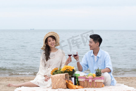 水果摄影照片_浪漫的青年夫妇坐在沙滩上喝红酒