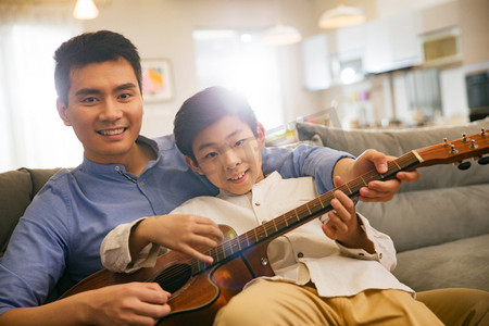 人物演摄影照片_父亲和男孩在弹吉他