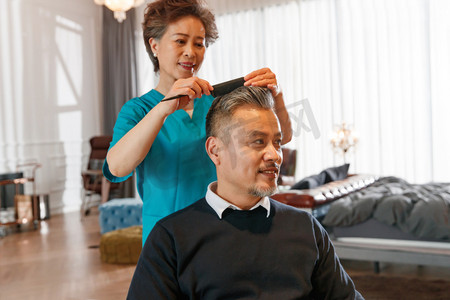 护工给坐轮椅的中年男士梳理头发