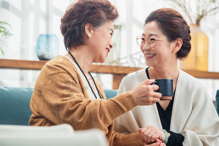 笑着的女人摄影照片_中老年闺蜜拿着杯子聊天