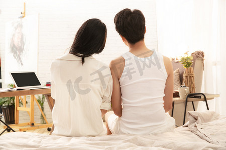 帅哥人物摄影照片_幸福的情侣坐在床上的背影