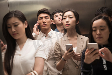 乘电梯摄影照片_商务青年男女乘电梯