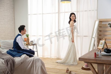卧室里新婚的丈夫欣赏妻子穿婚纱的样子