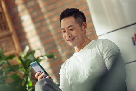 智能家居生活摄影照片_青年男人在家看手机