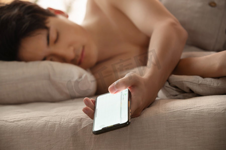 躺着图片摄影照片_玩手机玩到睡着的年轻男人