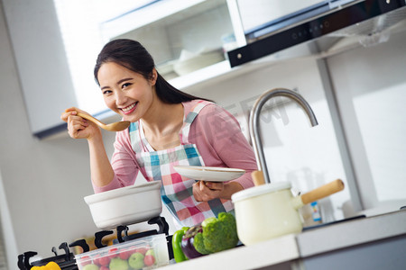 煲汤摄影照片_青年女人在厨房煲汤