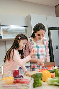 蔬菜蓝蔬菜摄影照片_年轻妈妈和女儿在厨房