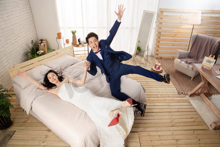 西装皮鞋摄影照片_兴奋的新婚夫妇倒在床上