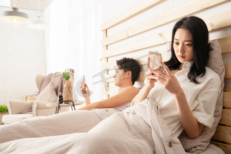 年轻情侣在床上使用手机